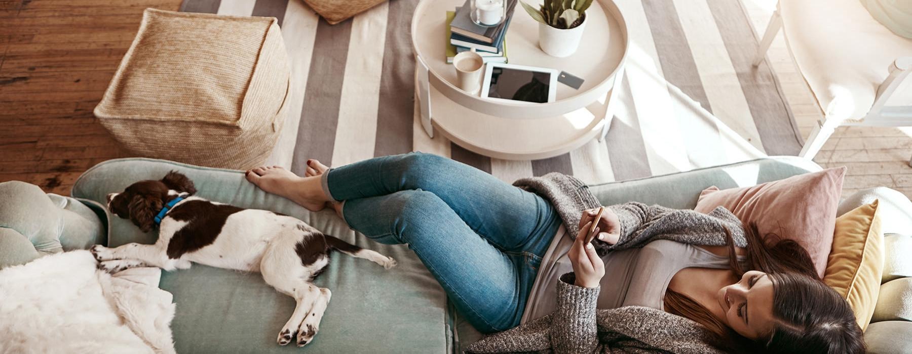 a person lying on a couch with a dog